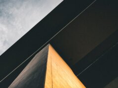 low-angle photography of black and brown concrete building under cloudy ble sky