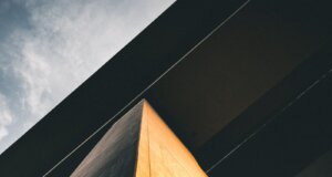 low-angle photography of black and brown concrete building under cloudy ble sky