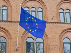 a european flag flying in front of a brick building